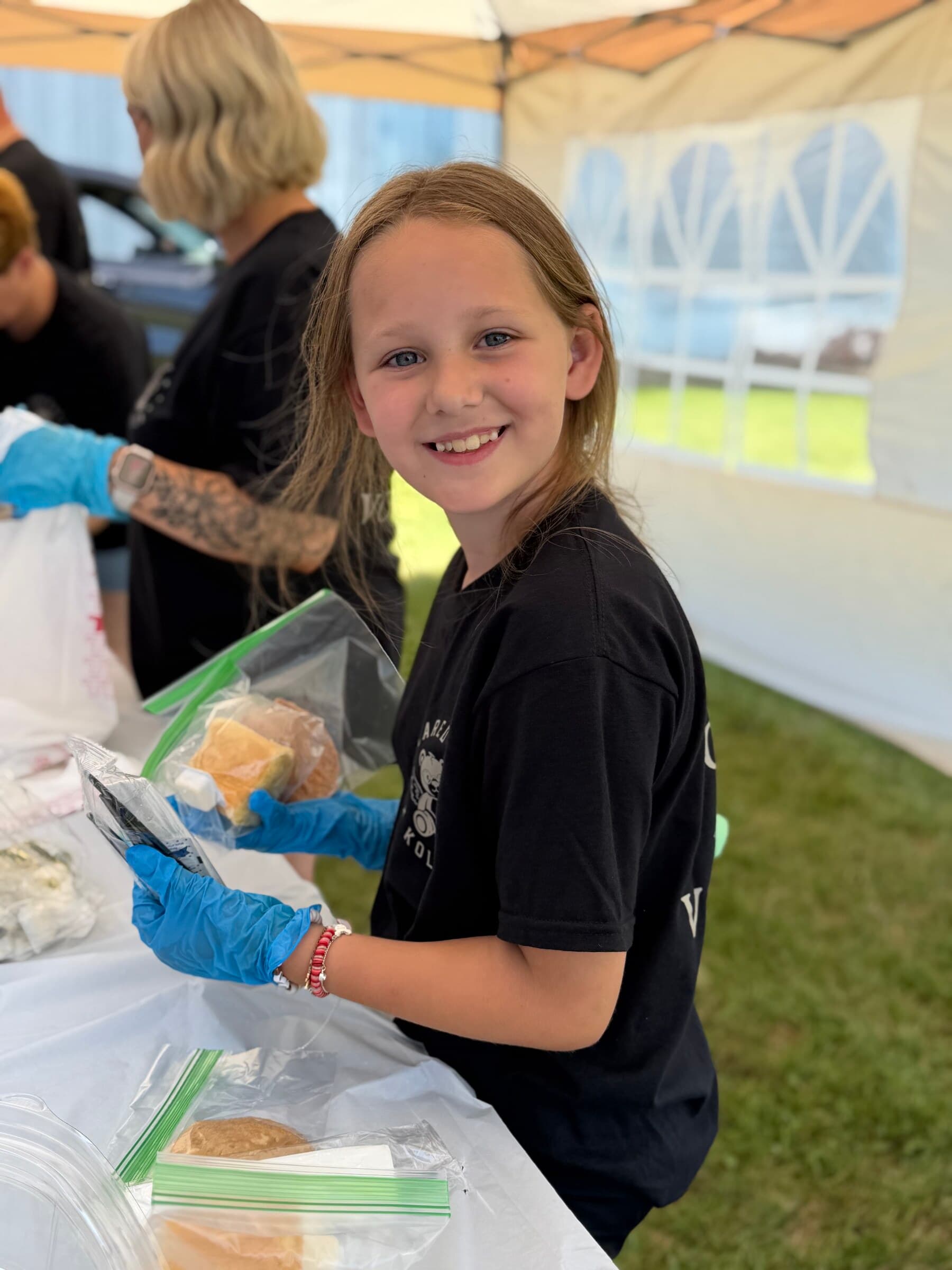 A young volunteer smiling while packaging cornbread at the BBQ