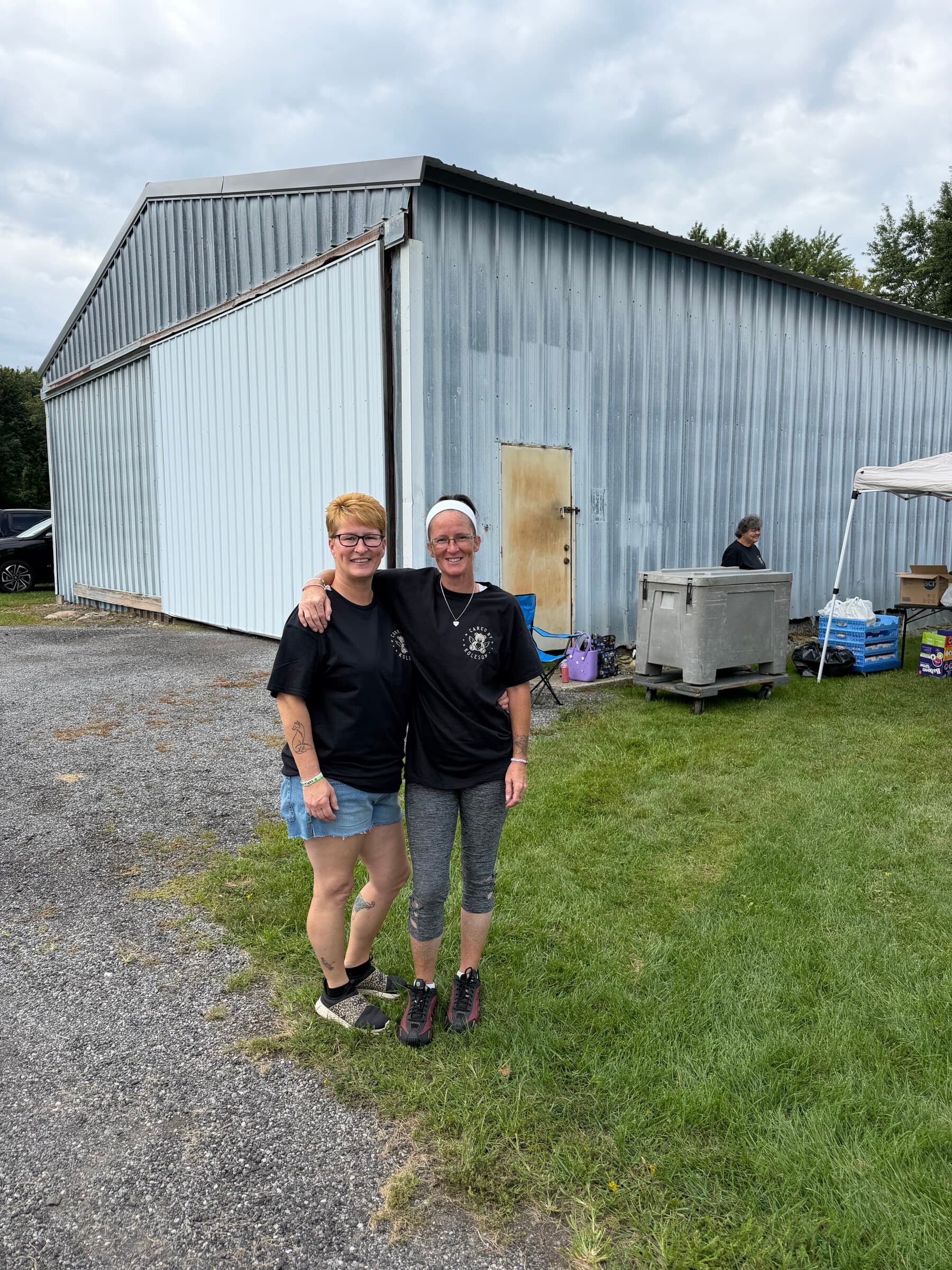 Two volunteers standing arm-in-arm outside the event tent