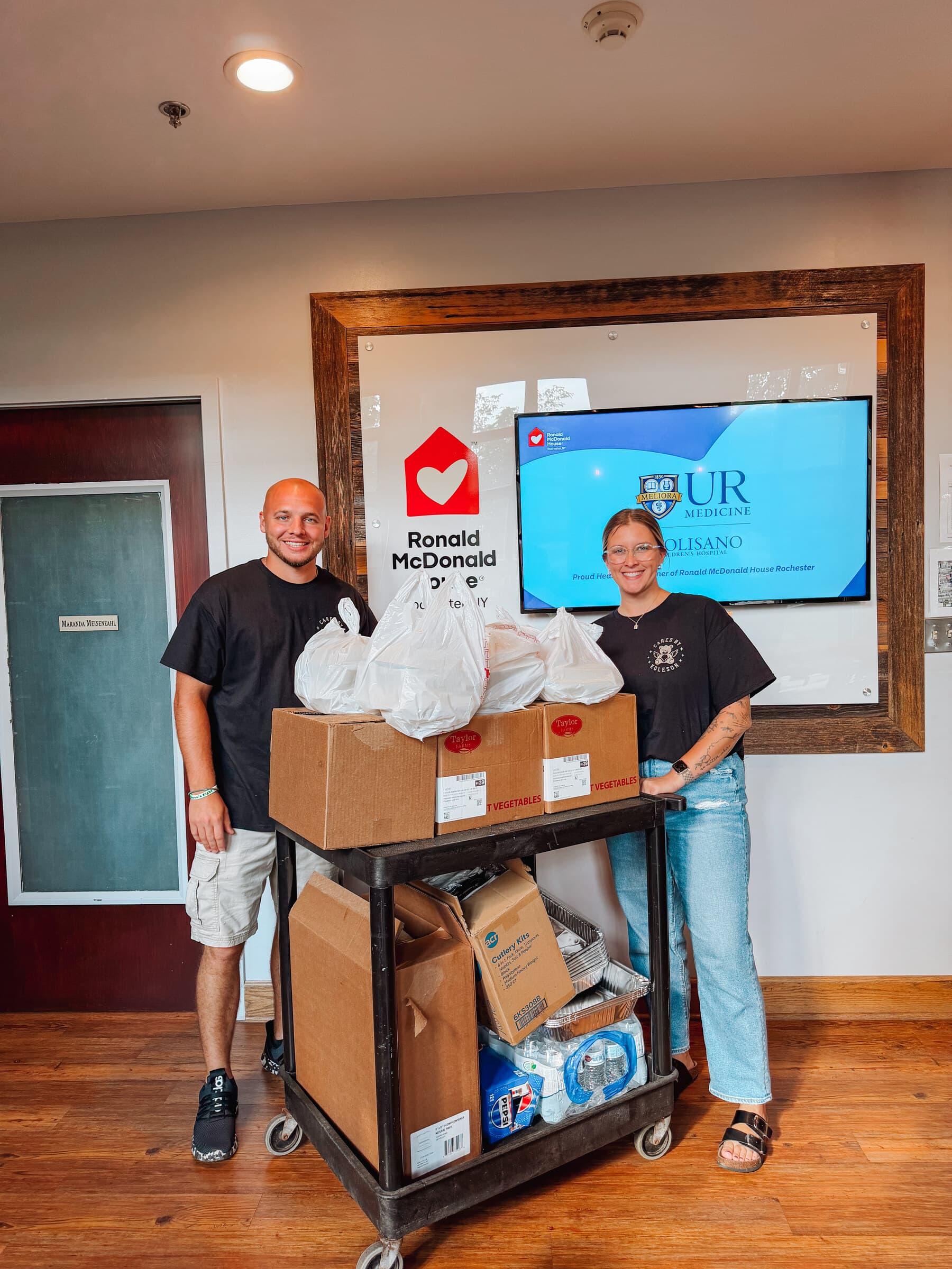 Brady and Dominique with a cart of meals and kitchen supplies inside Ronald McDonald House Rochester